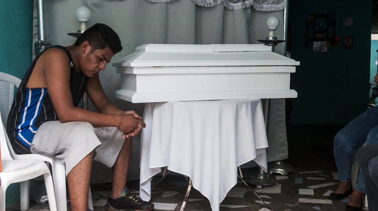 Nelson Gabriel Lorio permanece junto al ataúd de su hijo, de 15 meses, en su casa en Managua (Nicaragua)