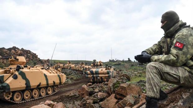 Un miembro del ejército turco junto a unos carros de comabte en la frontera con Siria