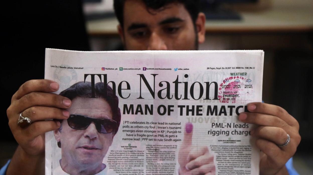 Un ciudadano lee un periódico que lleva a su portada una foto del exjugador de críquet Imran Khan