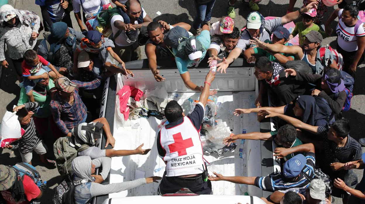 Personal de la cruz roja entrega agua a migrantes hondureños que continúan recorriendo otro tramo del territorio mexicano