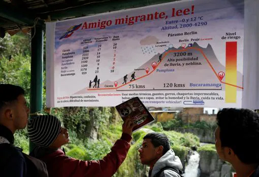 Venezolanos miran una pancarta con información sobre la ruta de Cúcuta a Bucaramanga