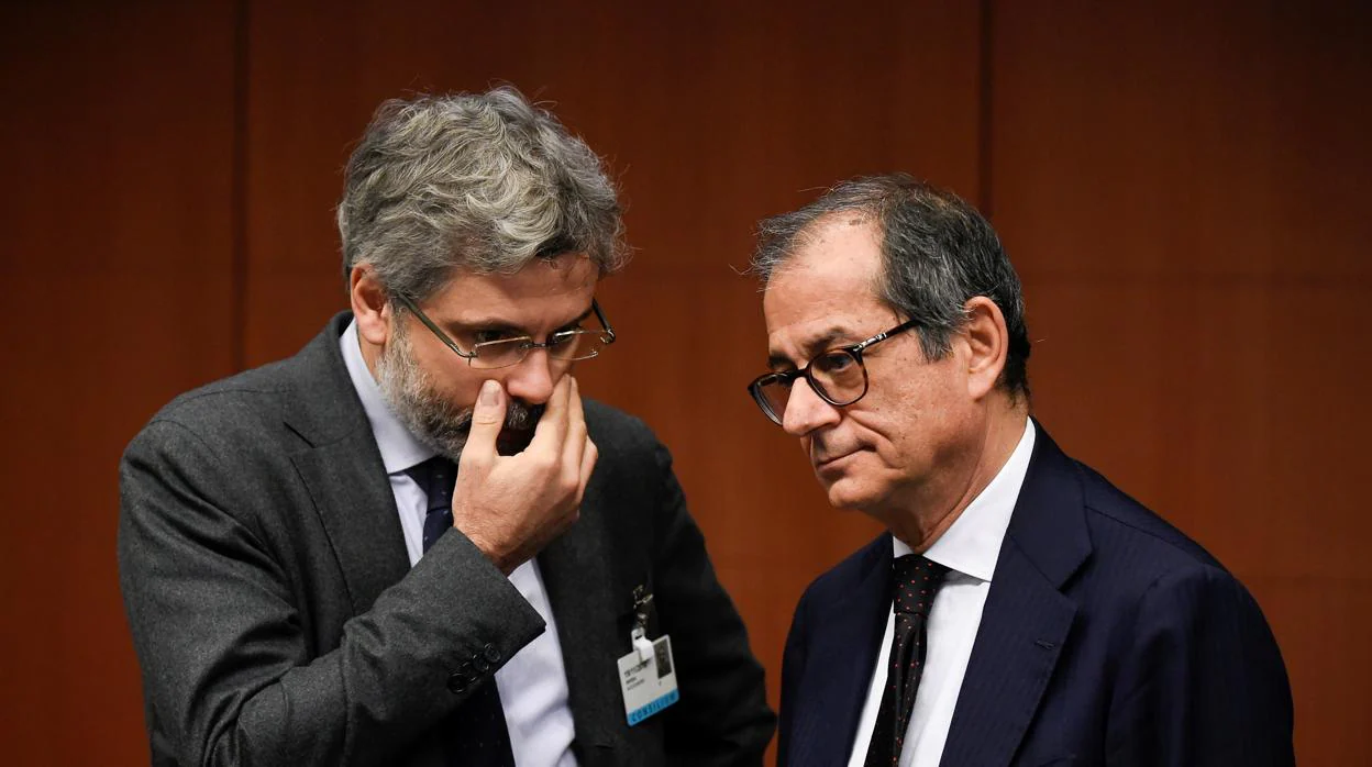 Un asesor habla con el ministro italiano de Economía, Tria, en la reunión de ayer en Bruselas