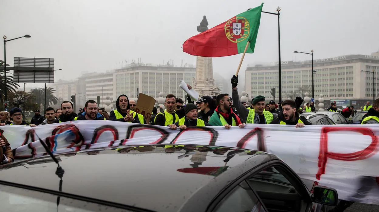Manifestantes del movimiento "chalecos amarillos" sostienen pancartas y banderas nacionales durante una protesta en Braga