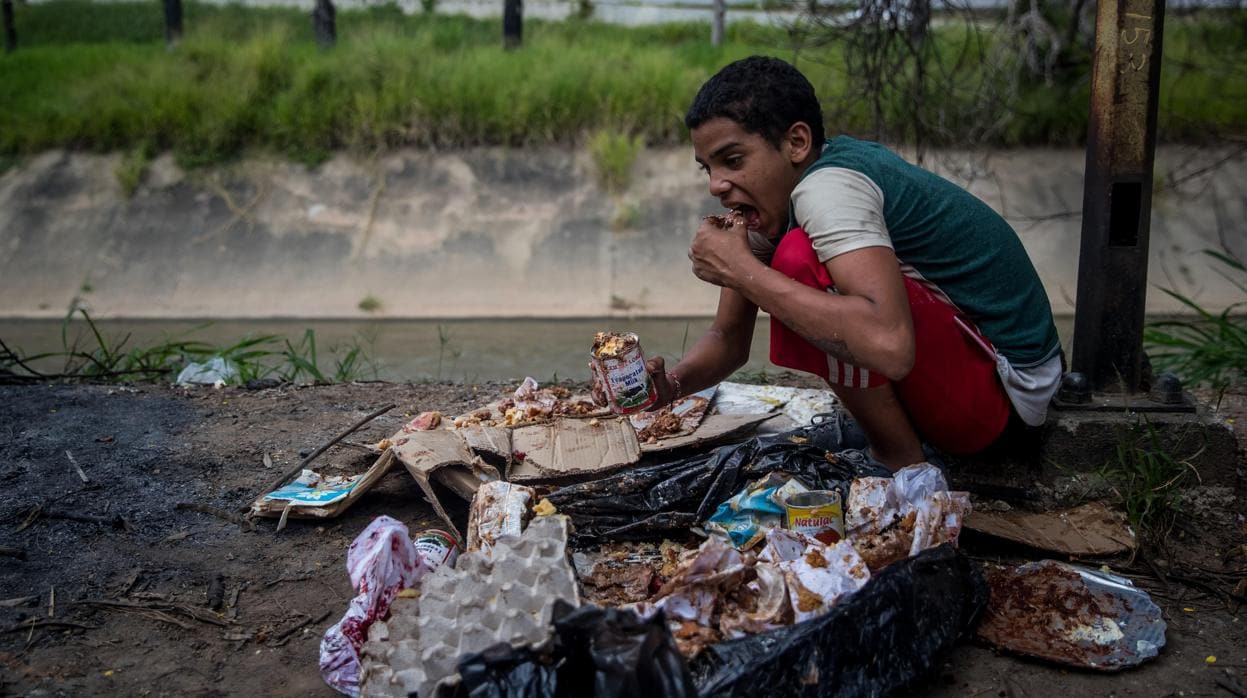 Un niño come de los restos de la basura en Caracas