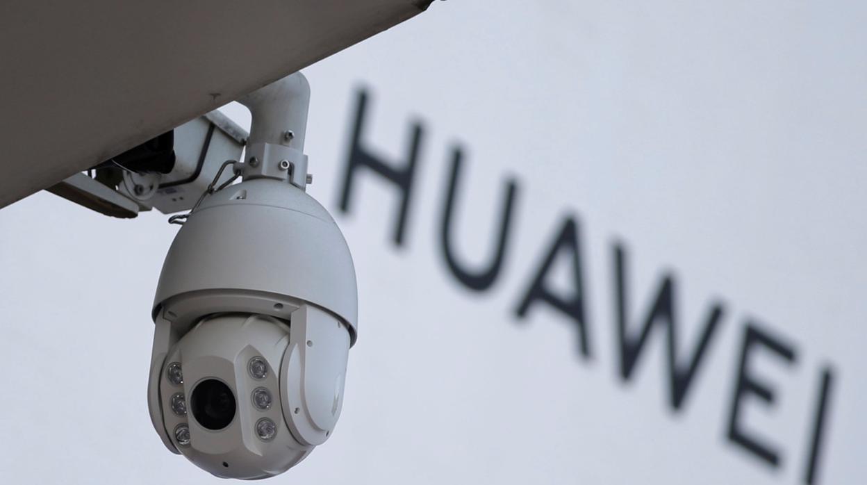 Una cámara de vigilancia junto a un cartel de Huawei frente a un centro comercial en Beijing