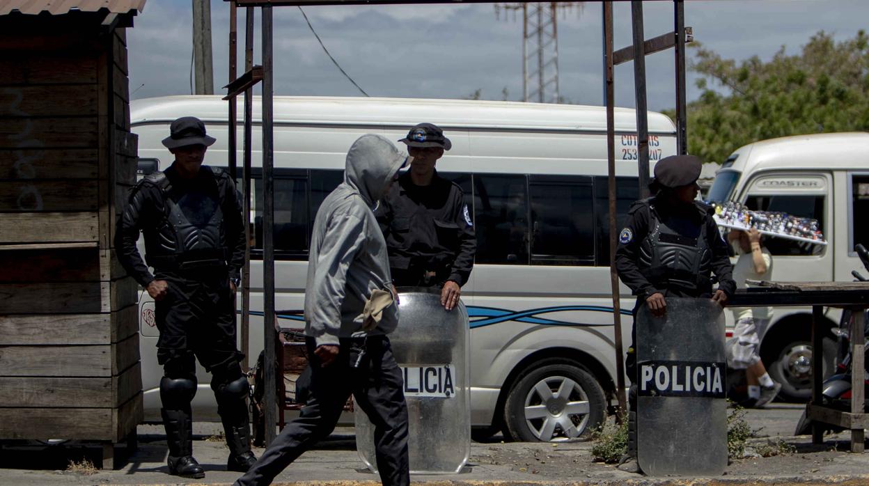 Agentes antidisturbios de la policía nacional resguardan una parda de autobú frente a la Universidad Centroamericana, en Managua