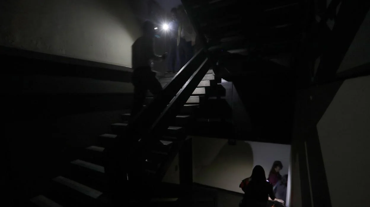 Un grupo de personas baja las escaleras en medio de la oscuridad al interior del edificio de la Asamblea Nacional