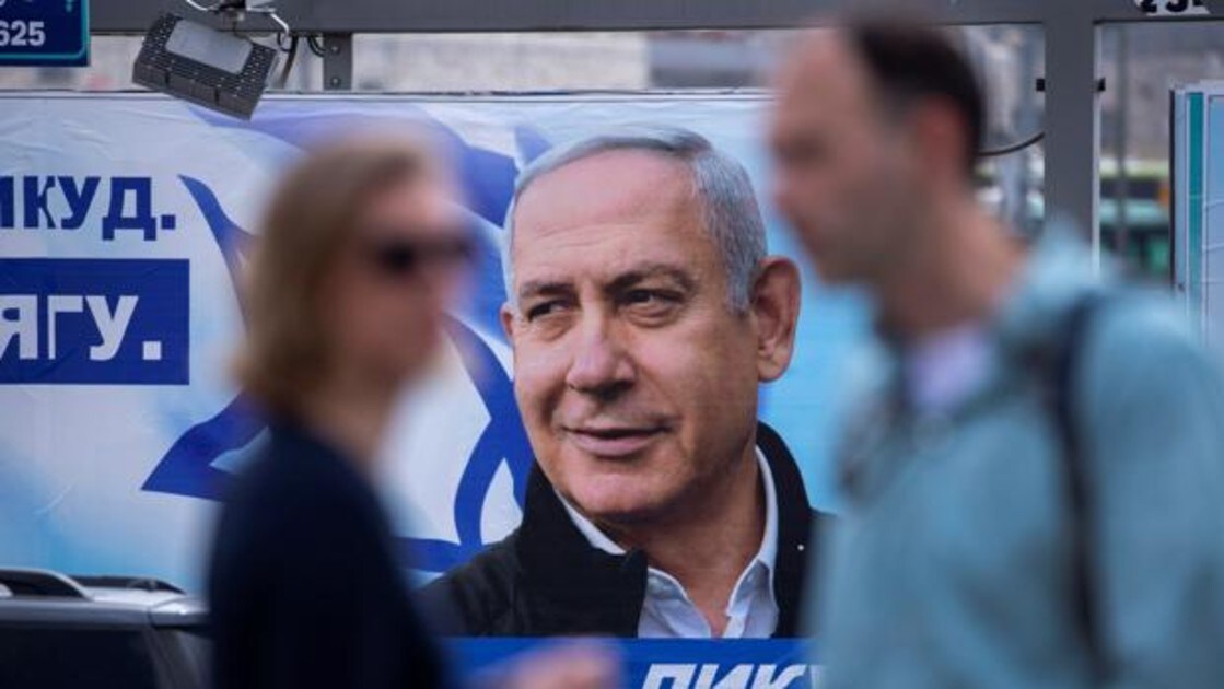Dos personas pasan frente a un cartel electoral escrito en ruso que muestra al primer ministro israelí, Benjamin Netanyahu, este viernes en Jerusalén