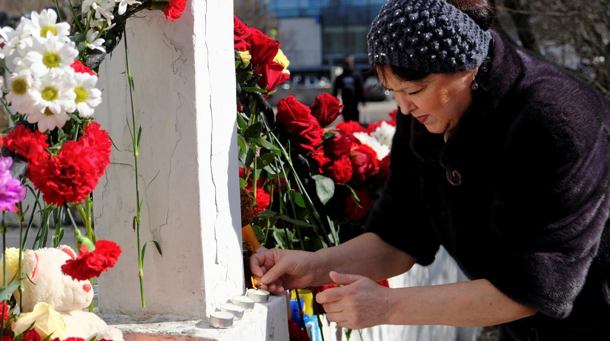 Una mujer pone flores en memoria de las víctimas del accidente del avión
