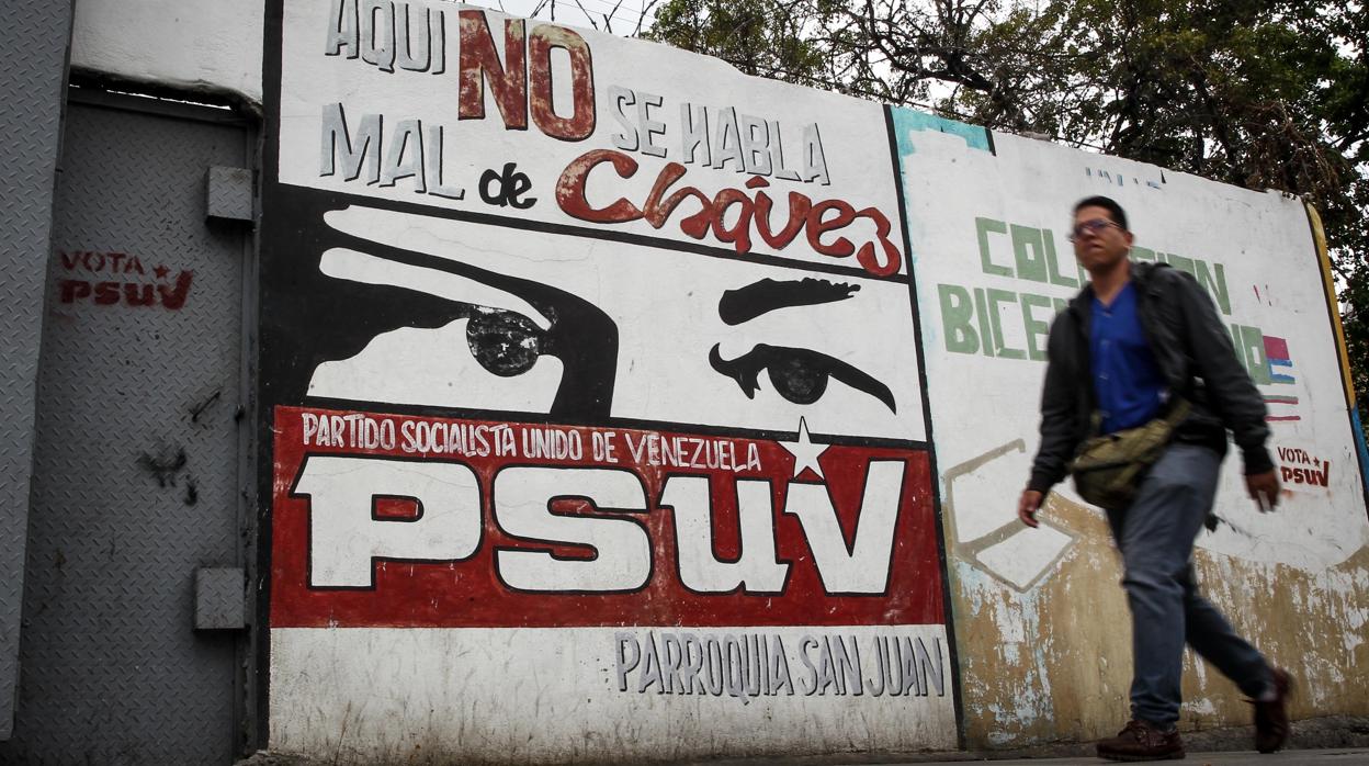 Un hombre pasa frente a un mural chavista en un barrio de Caracas