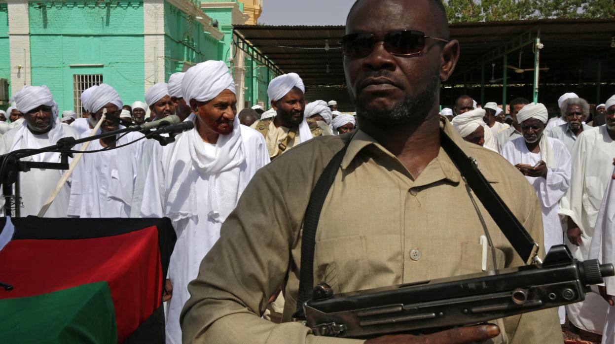 Un oficial armado vigila mientras el imán Sadiq al Mahdi lidera los rezos del Aíd al Fitr, que marca el final del Ramadán, este miércoles, en Omdurmán, Sudán