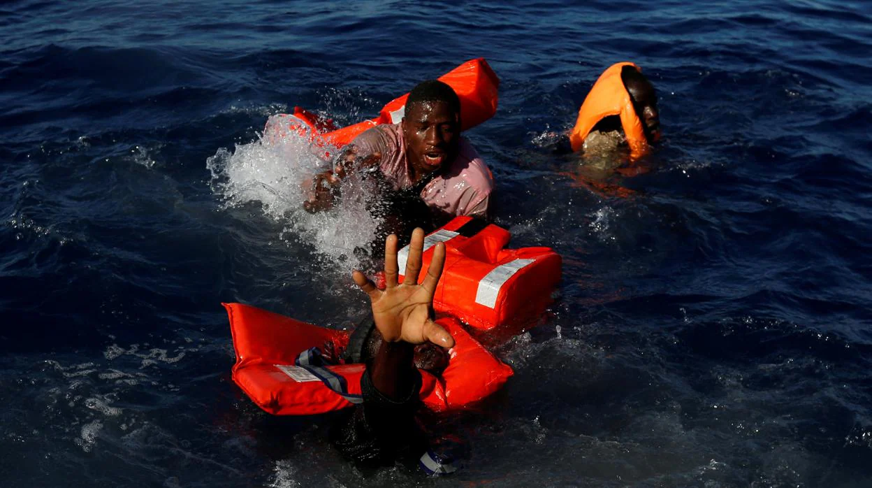 Tres tratan de mantenerse a flote tras el naufrafio de su embarcación en las costas de Libia, en 2017