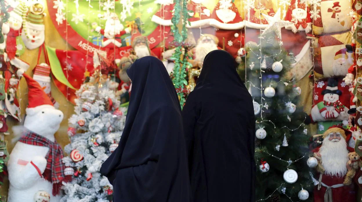 Dos mujeres observan una tienda decorada con motivos navideños, en Teherán, Irán,