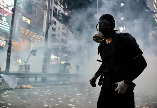 Un manifestante huye de la Policía huye bajo una nube de gases lacrimógenos en el céntrico distrito comercial de Causeway Bay