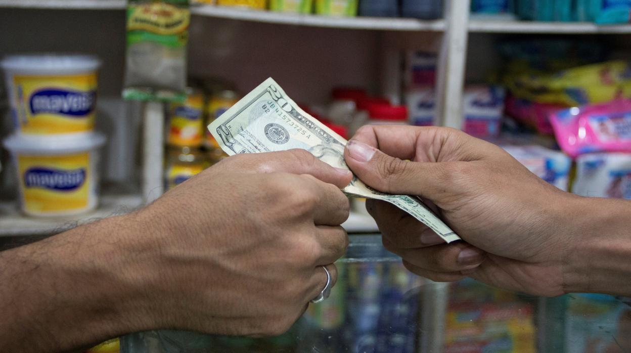 Una persona paga una compra con dólares en una tienda de alimentos en Maracaibo