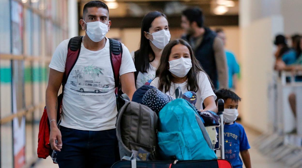 Una familia se protege con mascarillas del coronavirus en el aeropuerto de Santiago de Chile