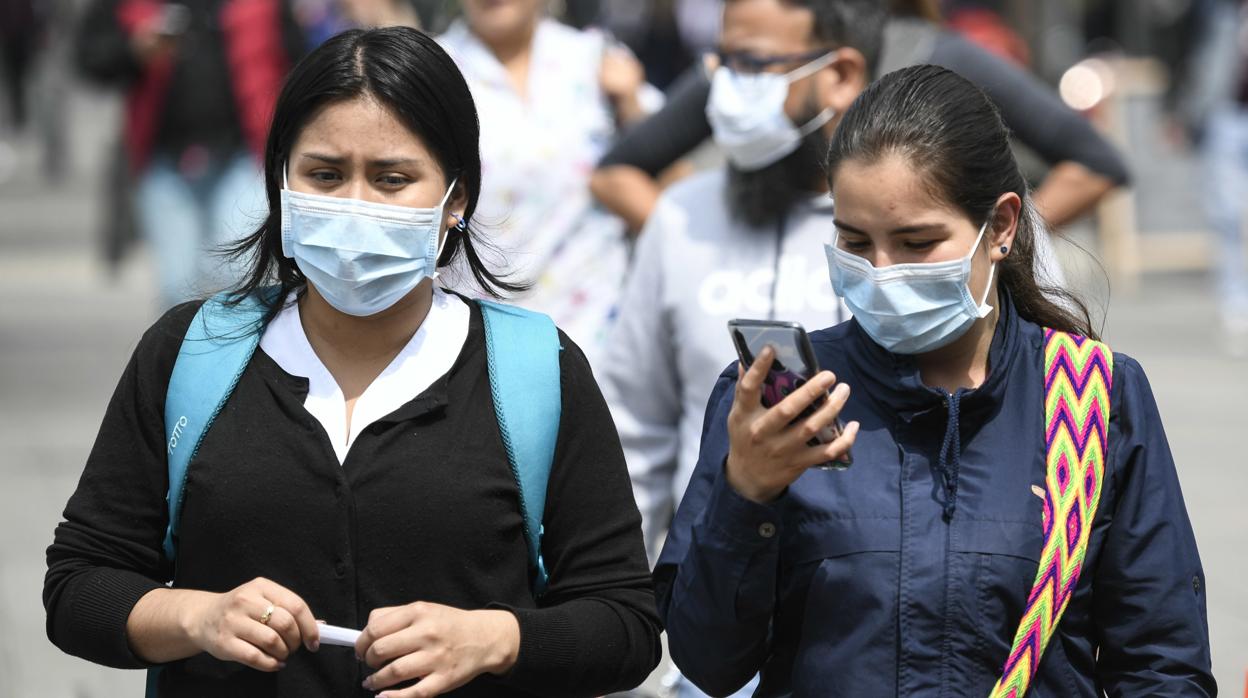 Dos chicas se protegen del coronavirus con una mascarilla en Bogotá