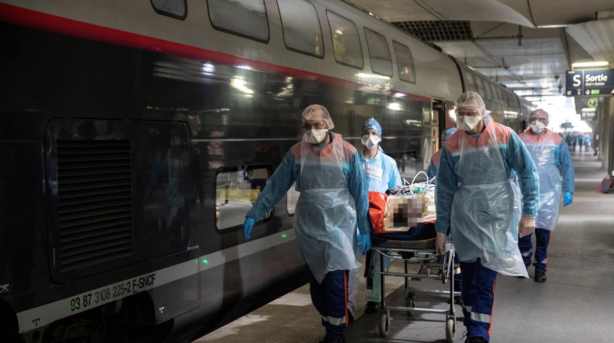 Personal médico introduce a un paciente en un tren de alta velocidad para trasladarlo de París a Bretaña