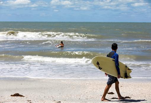 Unos surferos acudían este miércoles a coger olas en Treasury Island, en Florida, pese al cierre de las playas por parte de las autoridades del condado