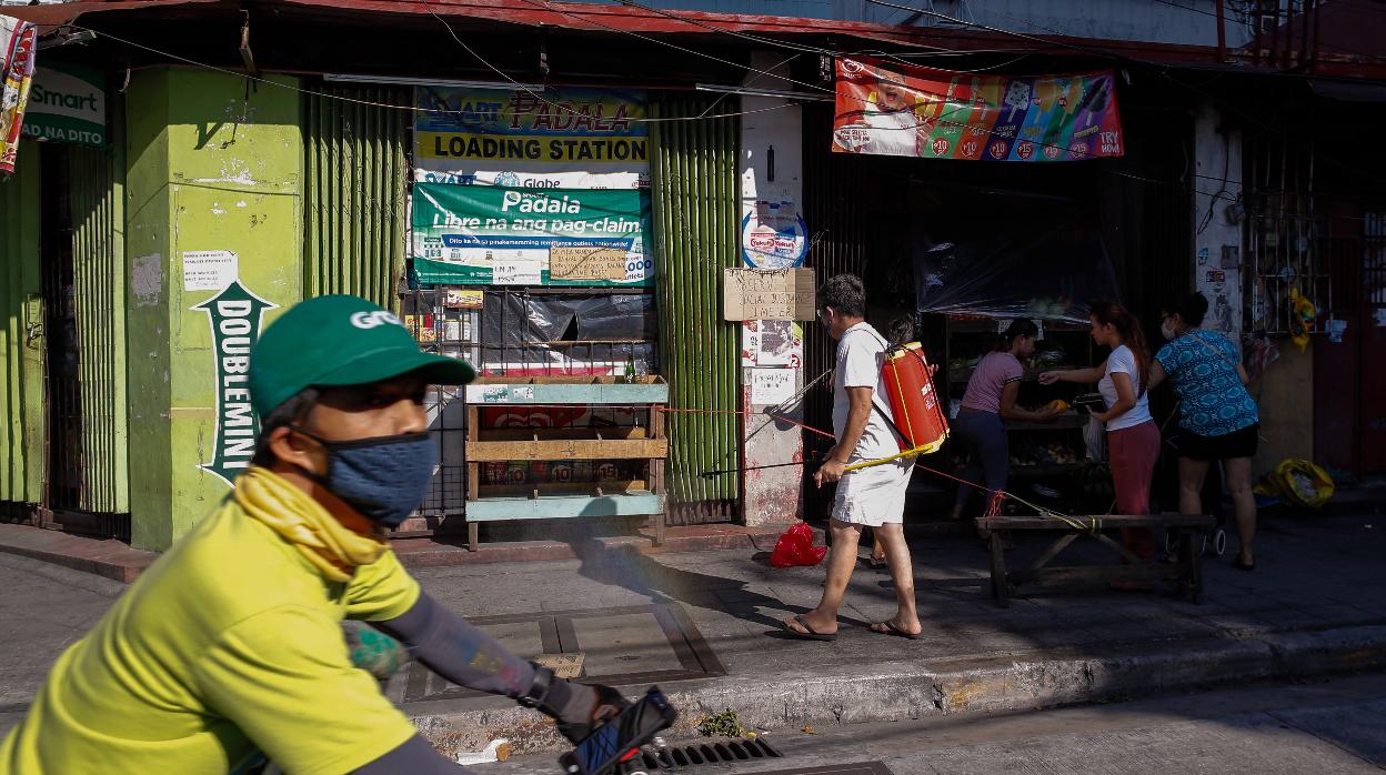 Un hombre rocía desinfectante a lo largo de una pequeña tienda en Makati, al sur de Manila (Filipinas)