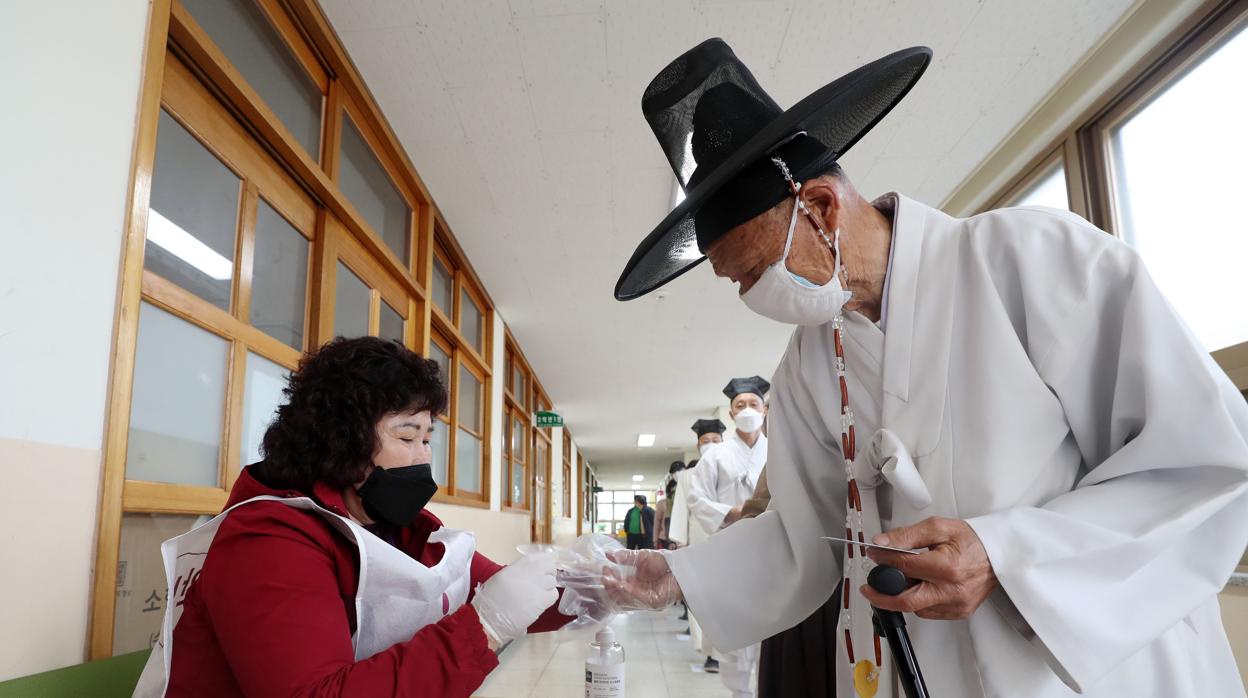 Un académico confunciano se coloca guantes para poder votar en las elecciones de Corea del Sur