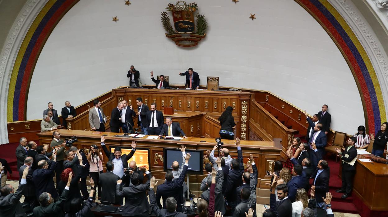 Diputados opositores levantan la mano para votar a favor de la reforma parcial del reglamento interior y debate durante la sesión extraordinaria de la Asamblea Nacional