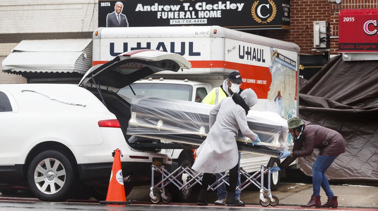 Tres personas mueven un ataúd en el exterior de la funeraria de Brooklyn