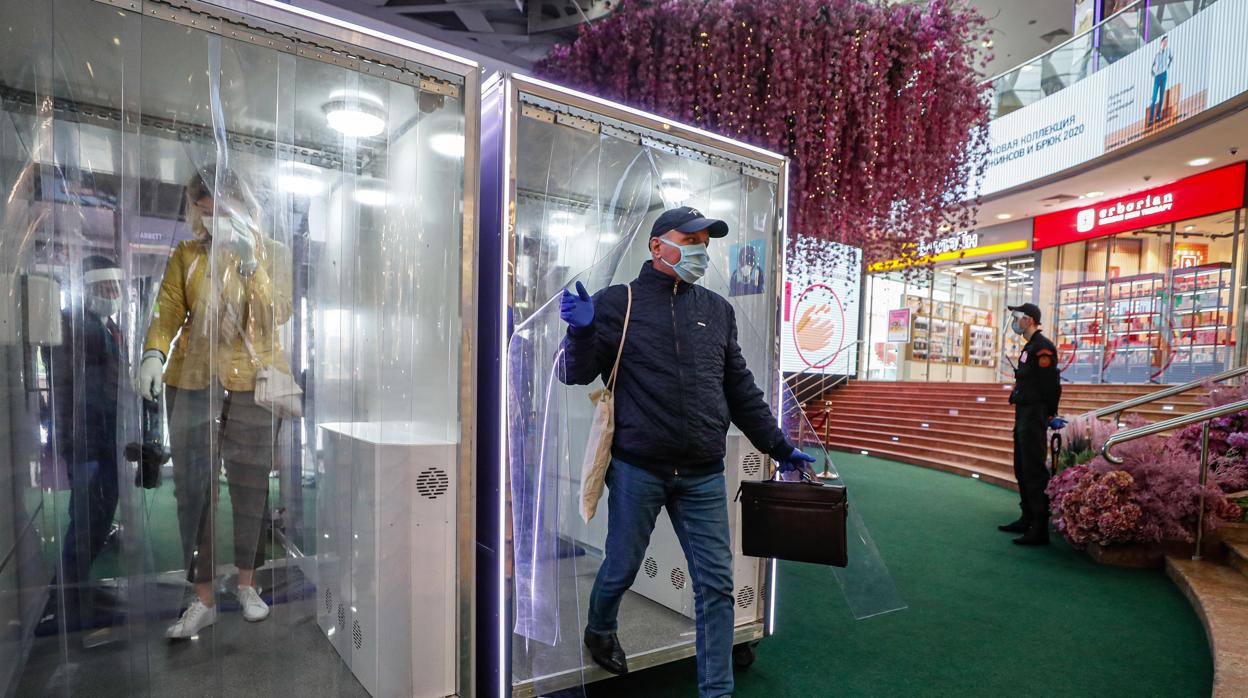 Un cliente accede a un centro comercial en Moscú tras pasar por una cabina de desinfección