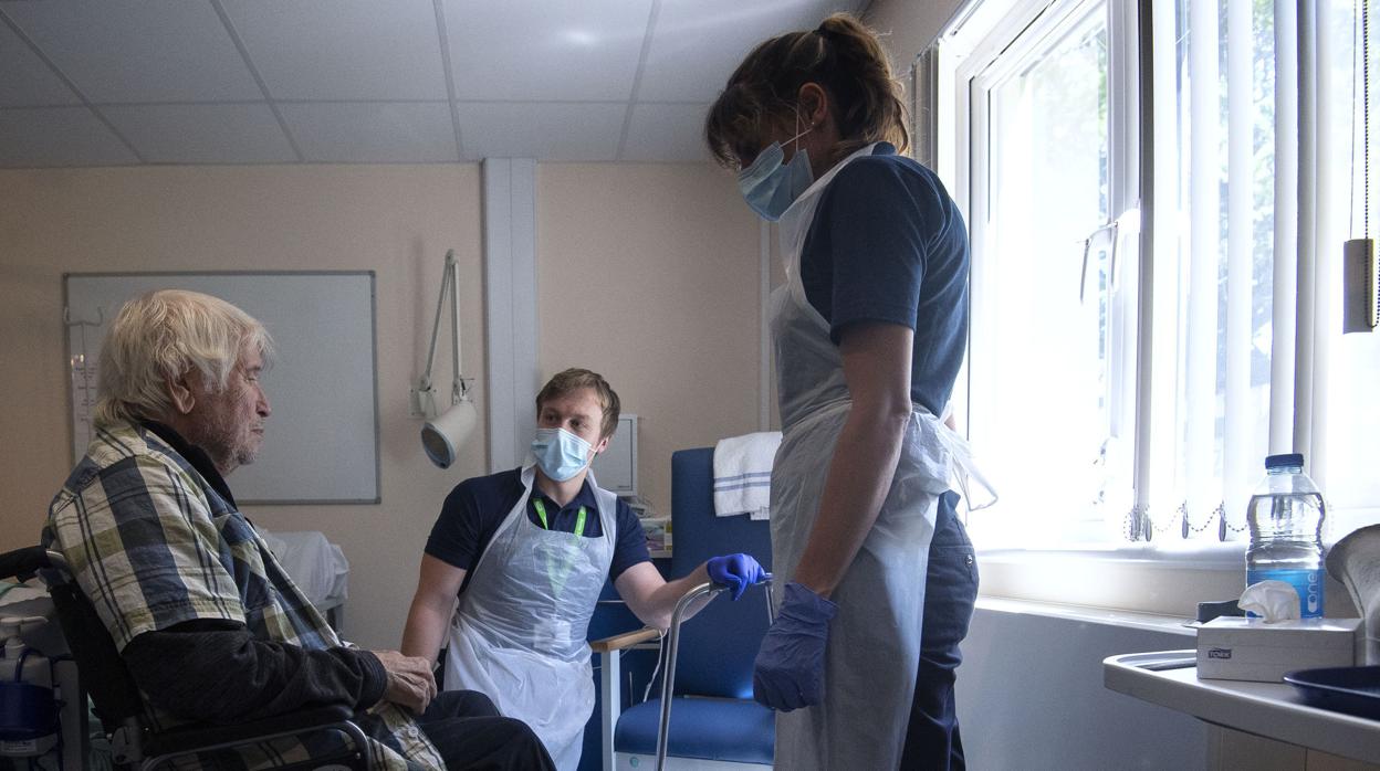 Dos miembros del personal sanitario tratan a un anciano en un hospital del Reino Unido