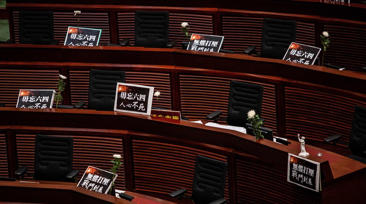 Los legisladores prodemocráticos dejan carteles y flores en sus asientos y abandona el pleno mientras continúa el debate en Hong Kong