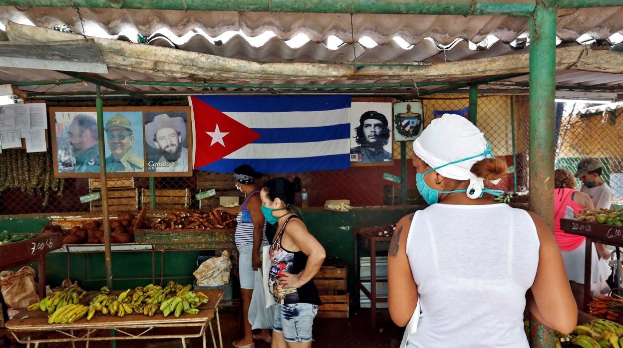 Una mujer, con mascarilla, espera para comprar en un mercado de La Habana