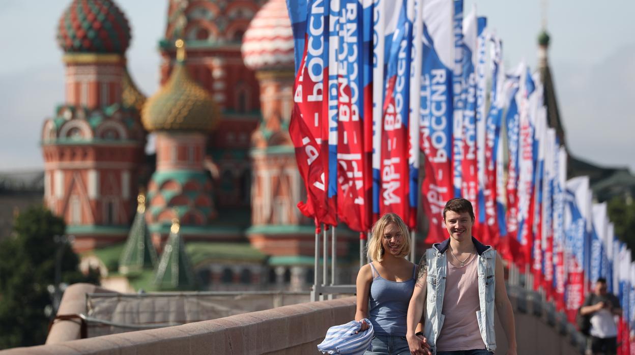 Una pareja camina por un puente con pancartas dedicadas a las celebraciones del Día de Rusia, en Moscú