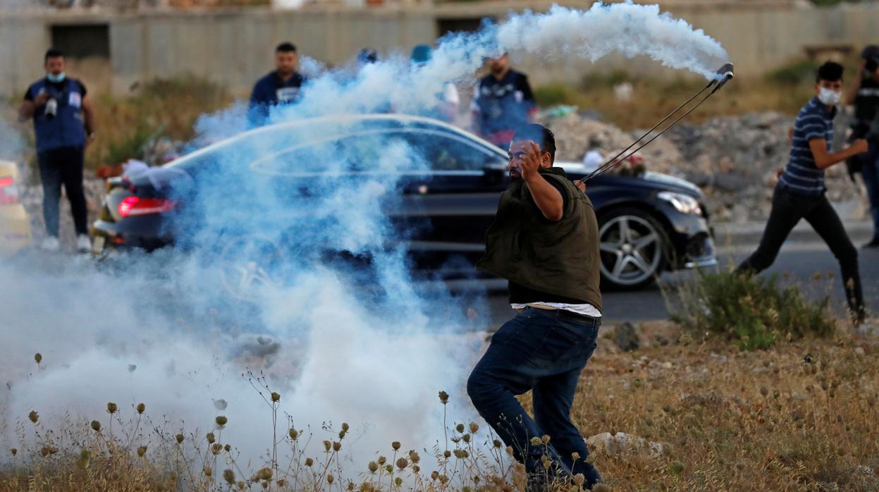 Un manifestante palestino devuelve a la Policía un bote de humo