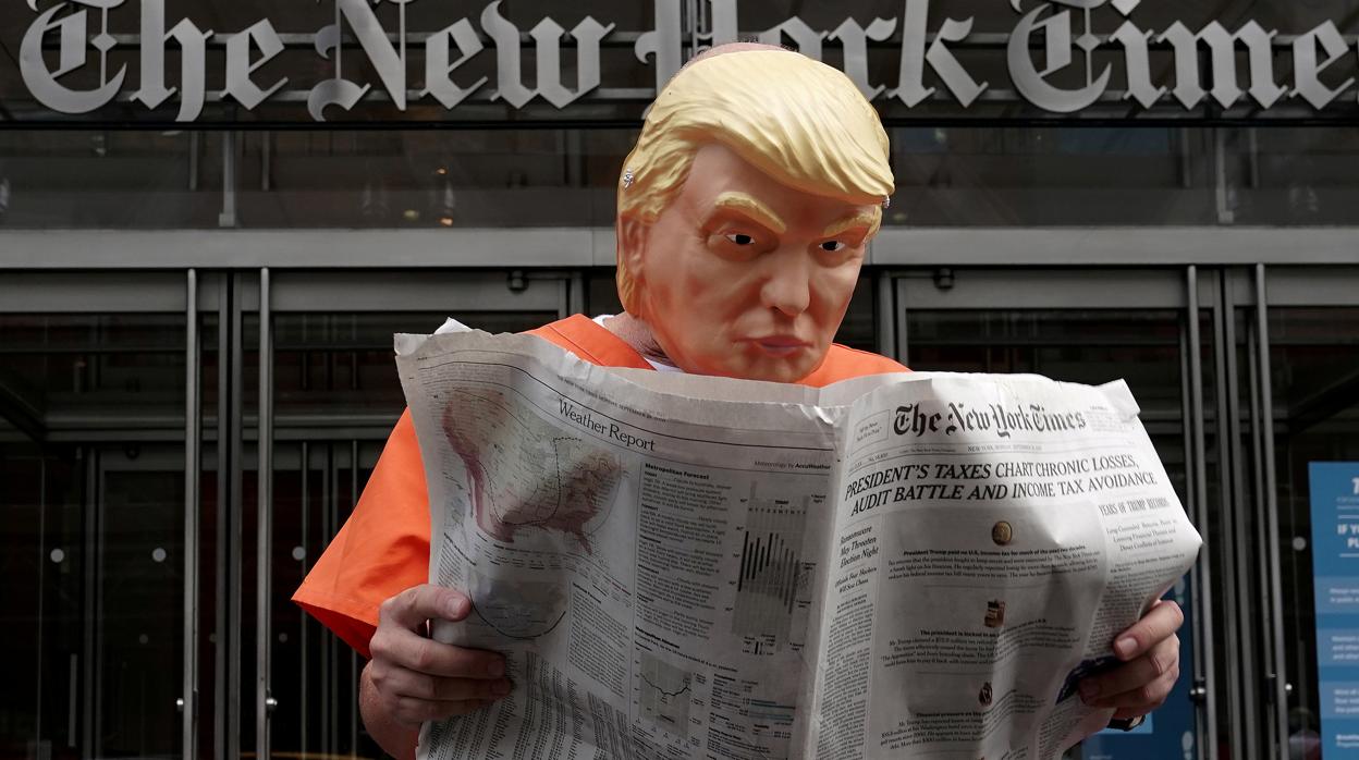 Un hombre con una careta de Trump lee el diario «The New York Times»