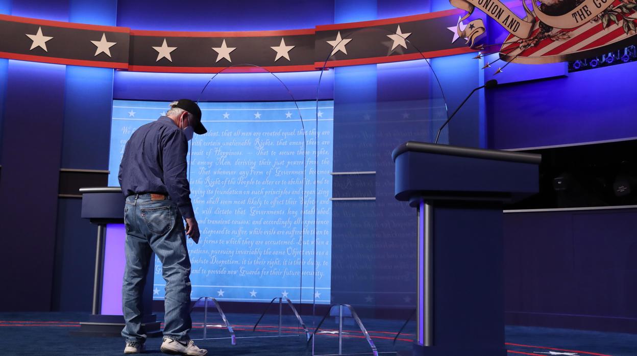 Un trabajador coloca una mampara entre los podios de los candidatos para el debate presidencial en EE.UU.