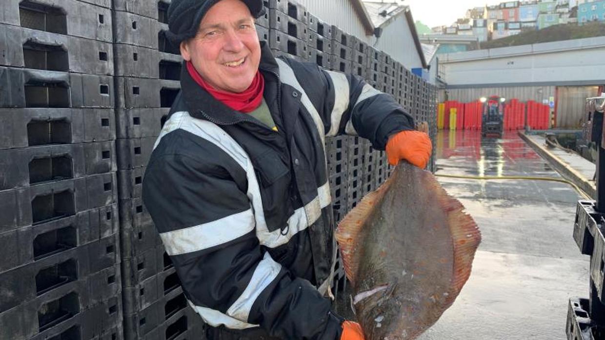 Un operario del puerto inglés de Brixham sostiene una platija recién pescada en el Canal de la Mancha por el arrastrero de vara Margaret of Ladram