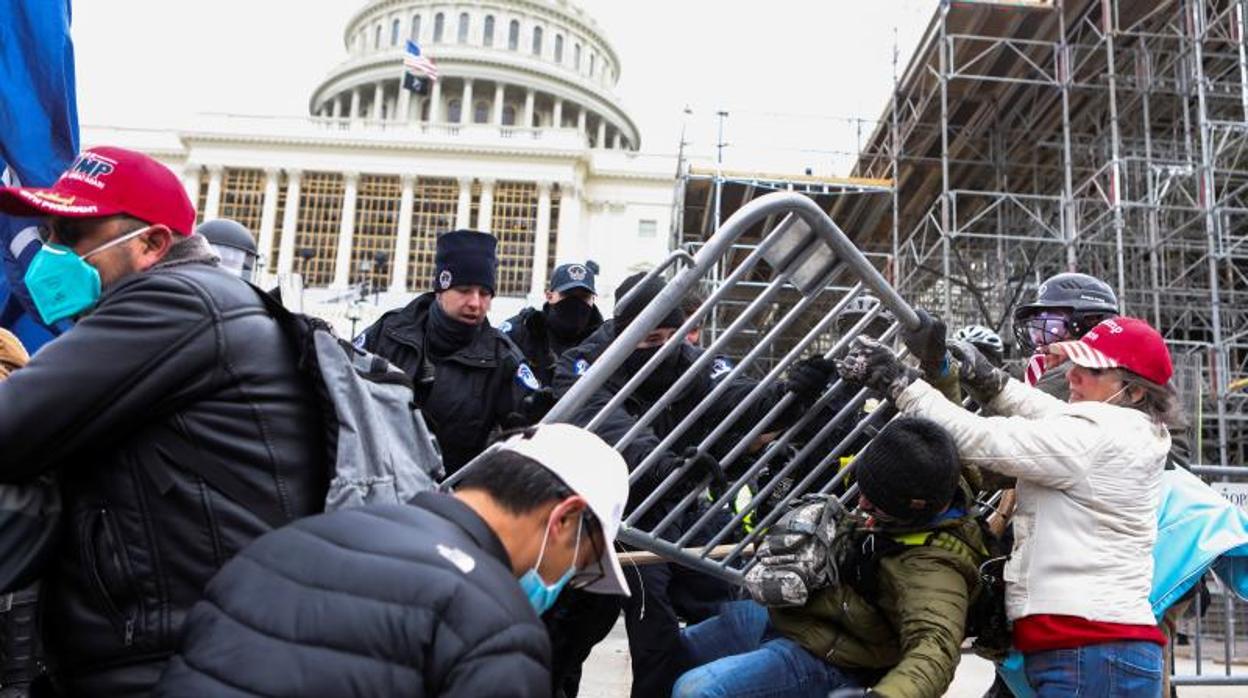 Los alborotadores forcejean con la Policía para superar la barrera que les separa del Capitolio