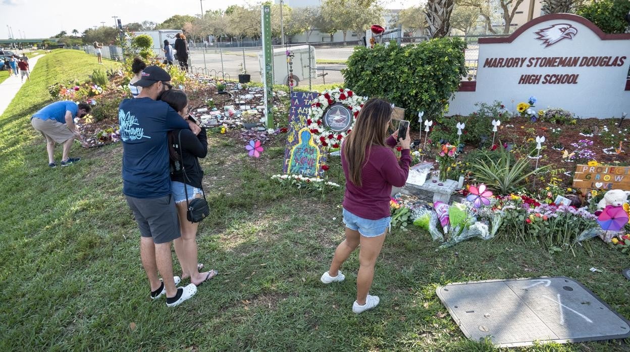 Una mujer toma una foto con su móvil al memorial improvisado frente a la escuela secundaria Marjory Stoneman Douglas, en Parkland