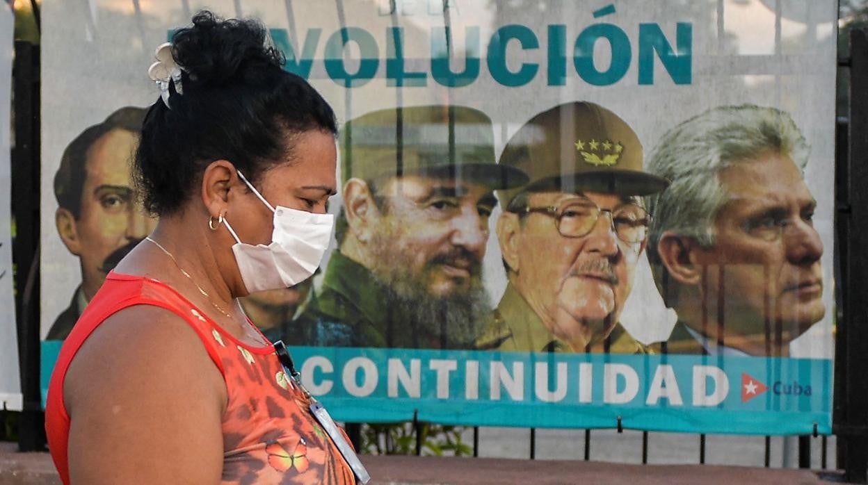 Una mujer camina frente a un mural con líderes comunistas cubanos en La Habana