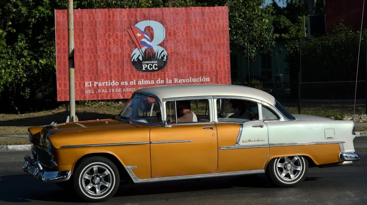 Un antiguo coche americano pasa por delante de un cartel del VIII Congreso del Partido Comunista de Cuba