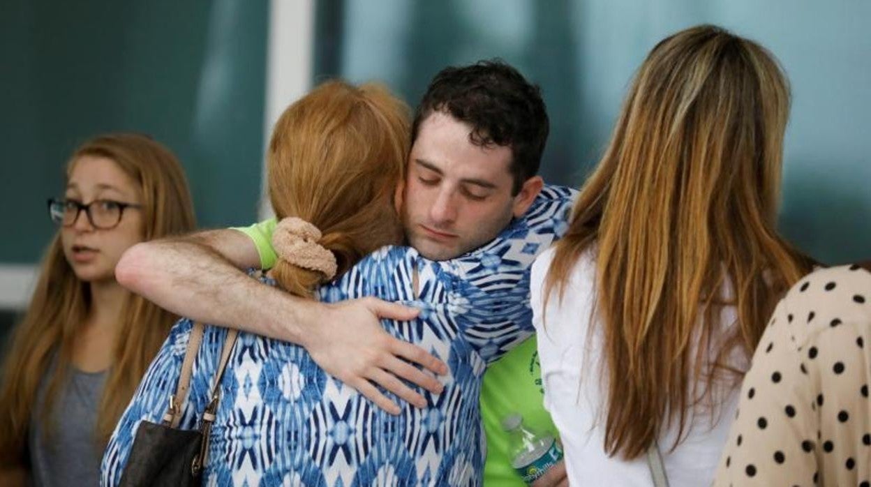 Dos personas se abrazan en el centro de reunificación familiar instalado tras el derrumbe del edificio en Surfside