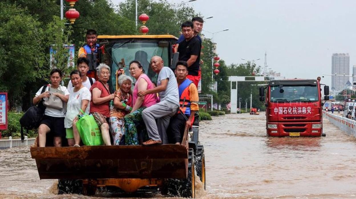 Rescatistas evacúan a los residentes con un cargador en un área inundada