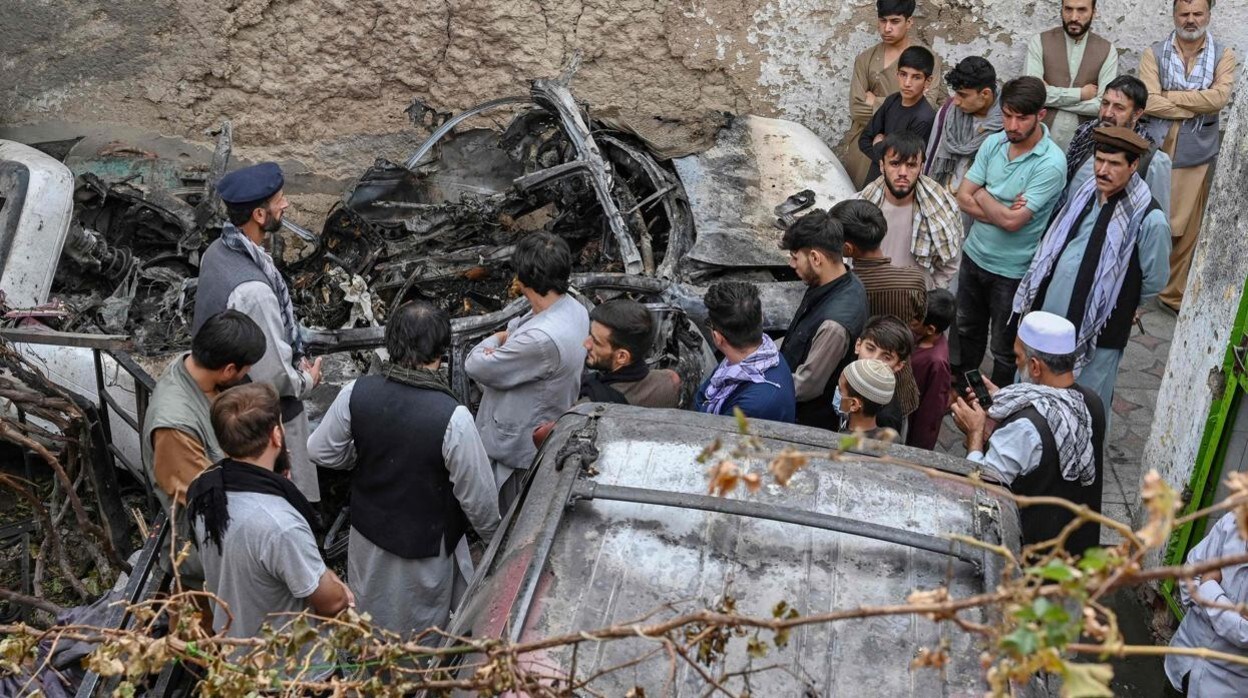 Vecinos y familiares se acercan al coche que recibió el misil de un dron de EE.UU. el 29 de agosto, en Kabul, en respuesta al atentado yihadista contra el aeropuerto unos días antes