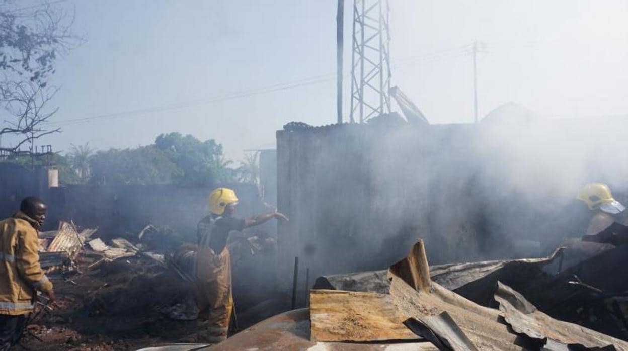 Los bomberos trabajan junto a los restos quemados tras la explosión de un camión cisterna de combustible en Freetown