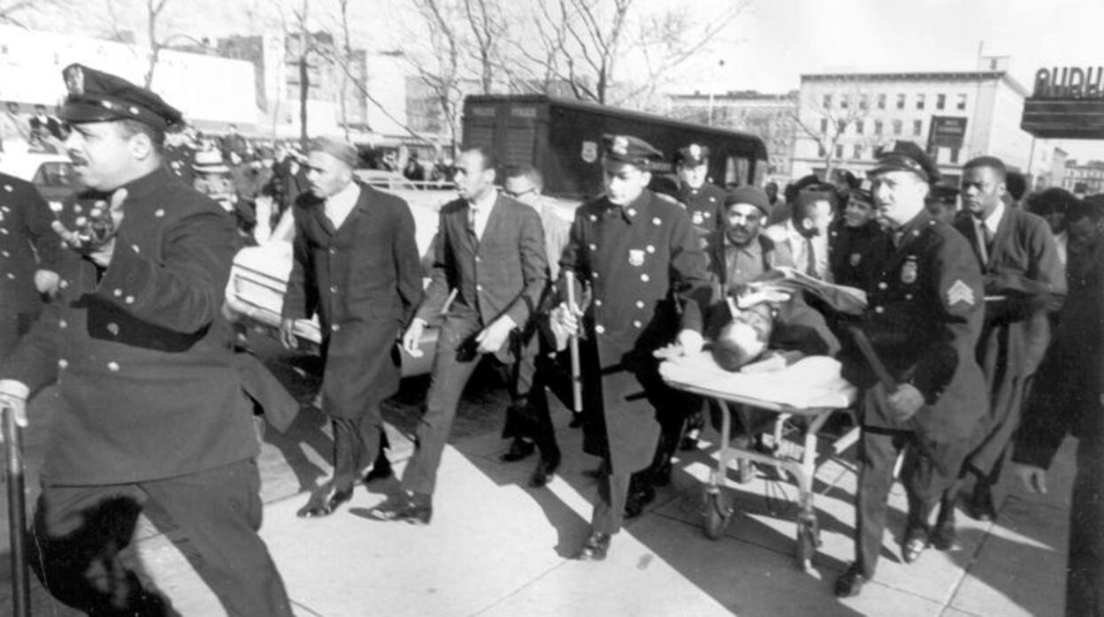 Un policia abre camino al cuerpo casi sin vida del lider nacionalista negro Malcom X en 1965