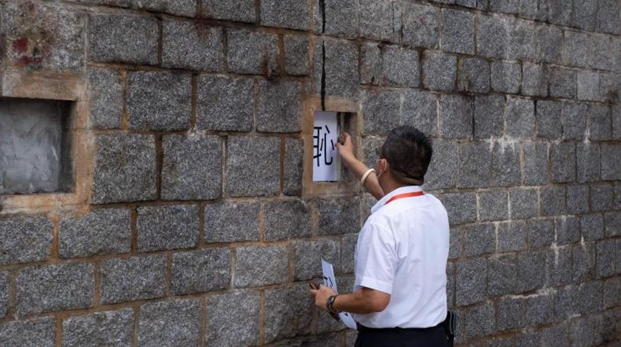 Un guardia de seguridad retira carteles impresos con el carácter chino «vergüenza» colocados en el sitio de una escultura contra los manifestantes por la democracia en la Plaza de Tiananmen, después de que fuera retirado de la Universidad Lingnan, en Hong Kong