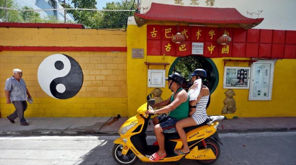 Una familia en moto pasa por una calle del barrio chino de La Habana