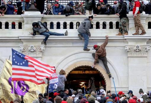 Manifestantes trepan por la fachada del Capitolio el 6 de enero de 2021