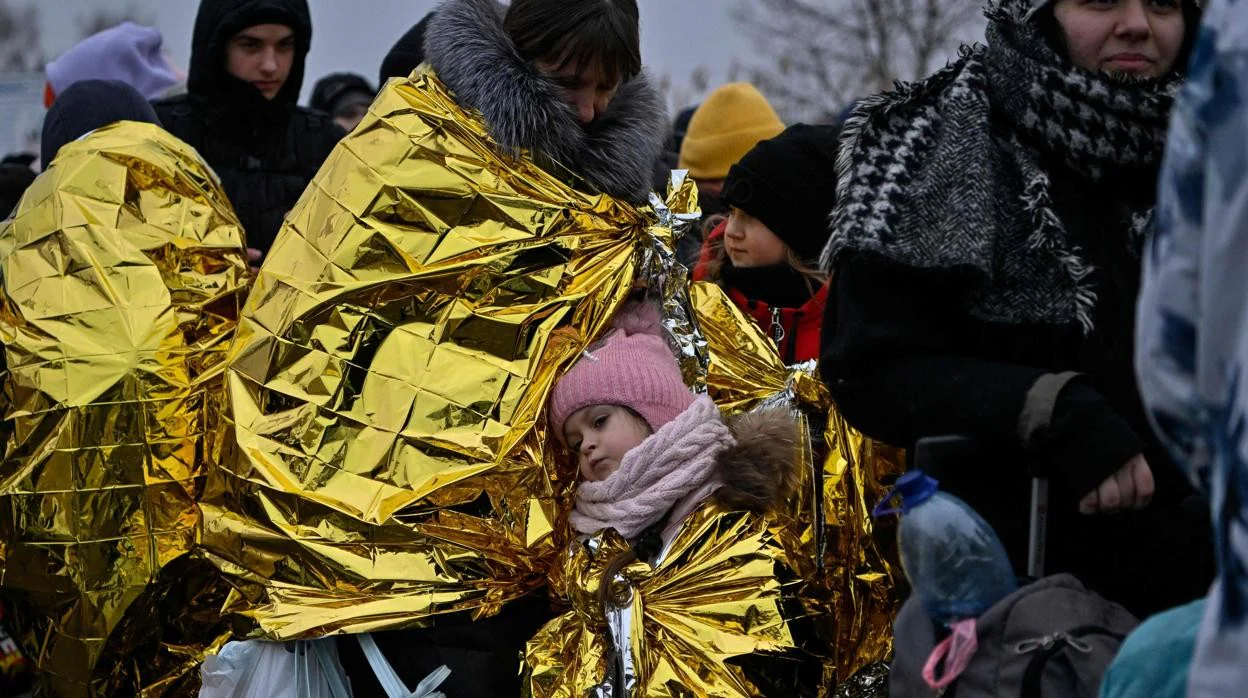 Un grupo de refugiados ucranianos se congrega a temperaturas bajo cero después de cruzar la frontera con Polonia