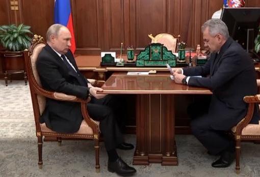 Putin sujeta con su mano la mesa donde mantiene una reunión con su ministro de Defensa